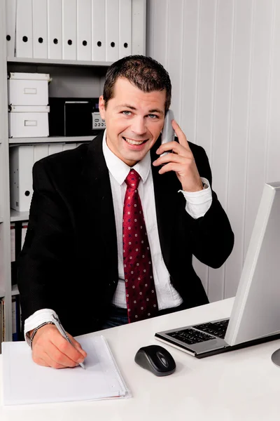 Бизнесмен в офисе с телефоном — стоковое фото