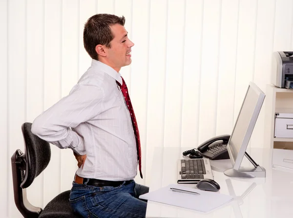 Человек в офисе с болью в спине — стоковое фото