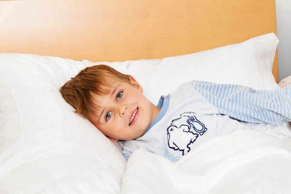 Barnet ligger i sängen i sovrummet — Stockfoto
