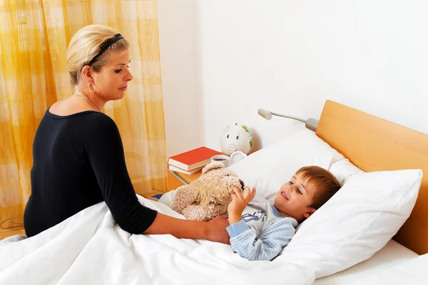 Matka a nemocné dítě v posteli. — Stock fotografie