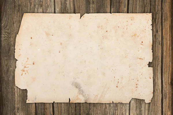 Papel velho danificado em um fundo de madeira — Fotografia de Stock