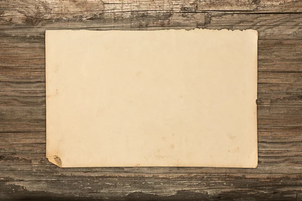 Papel viejo descolorido sobre un fondo de madera — Foto de Stock