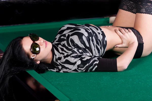 Pretty brunette model in dark underwear on a pool table — Stock Photo, Image