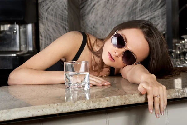 Vacker brunett flicka i solglasögon med ett glas vodka — Stockfoto