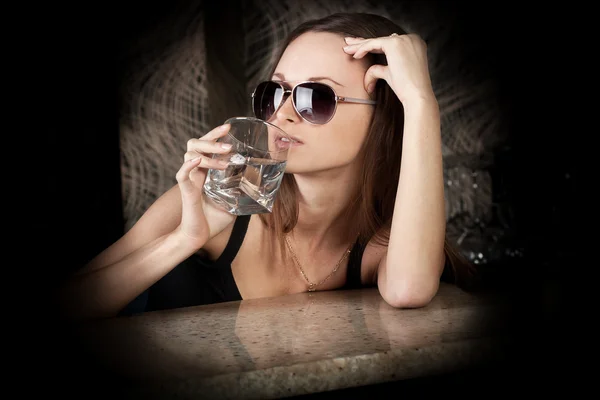 Güneş gözlüklü bir bardak votka ile şehvetli esmer kız — Stok fotoğraf