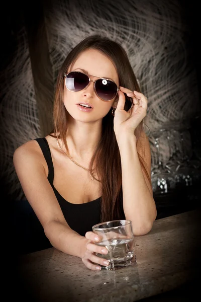 Stijlvolle jonge meisje in zonnebril met een glas wodka — Stockfoto