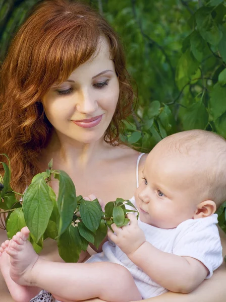 Bela mãe com um bebê em um jardim — Fotografia de Stock