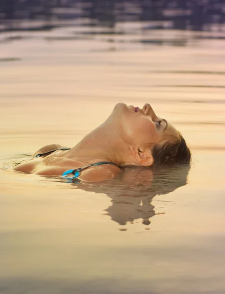 Sexig tjej avkopplande i vatten på sunset — Stockfoto