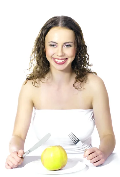 Schöne junge Frau isst einen Apfel am Tisch auf weißem Hintergrund — Stockfoto