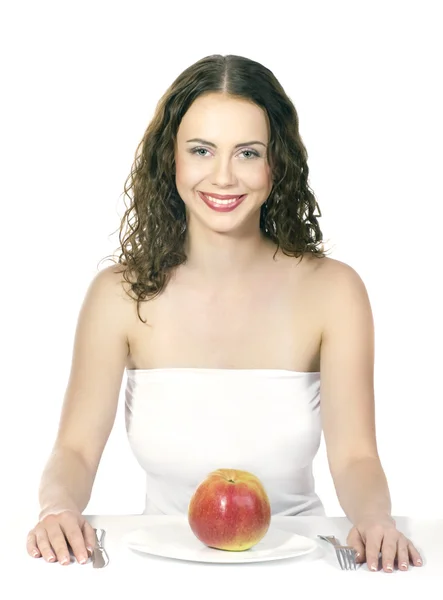 Hermosa mujer joven comiendo una manzana en la mesa en el fondo blanco — Foto de Stock