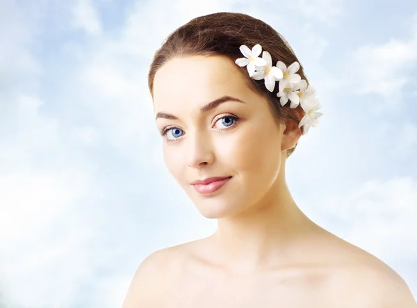 Vacker kvinna med blommor i hennes hår och ren hud — Stockfoto