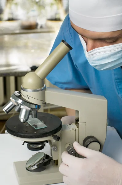 Um médico ou cientista como ele estuda algo através de um microsc — Fotografia de Stock
