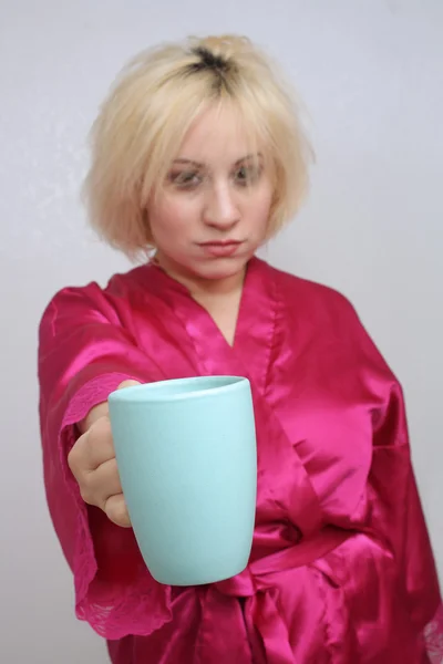 Mürrische Blondine hält ihre Kaffeetasse hoch — Stockfoto