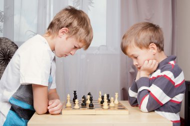 Two boys playing chess at home