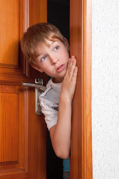 Surprised boy peeks from behind door — Stock Photo, Image