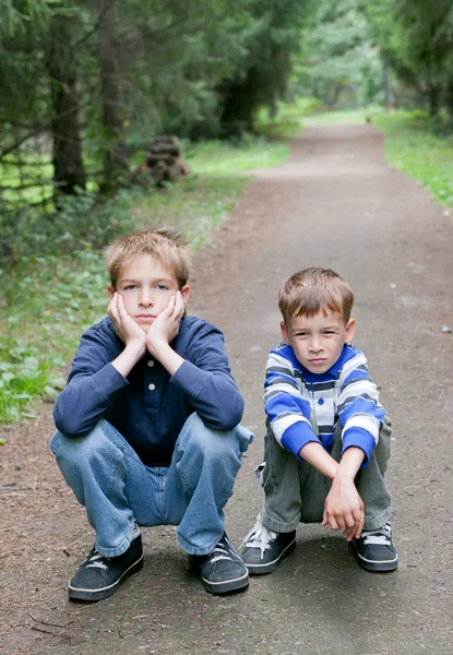 Два серьезных брата сидят на краю дороги — стоковое фото