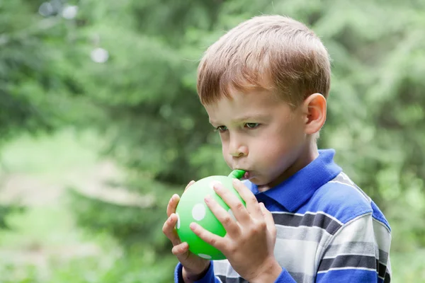 Junge lässt Luftballon in Park aufblasen — Stockfoto