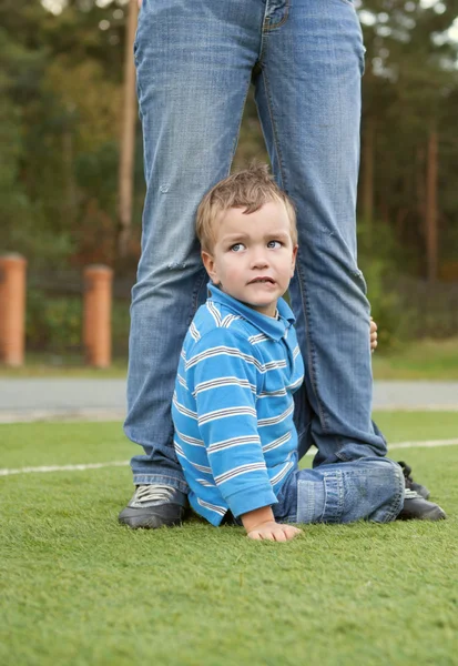 Verängstigter Junge sitzt einem Erwachsenen zu Füßen — Stockfoto