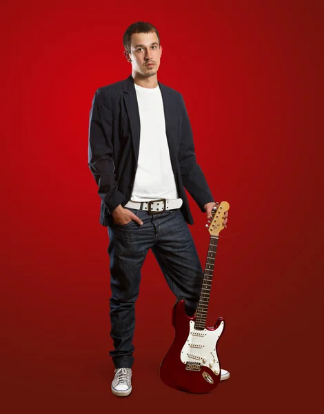 Stilvoller Mann mit Gitarre blickt in die Kamera — Stockfoto