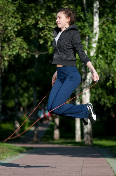 Jumping woman with skipping rope at park — Stock Photo, Image
