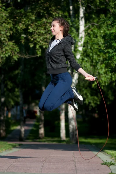 Skákání žena s švihadlo v parku — Stock fotografie