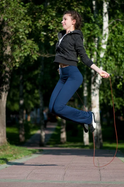 Saltar mujer con saltar la cuerda en el parque — Foto de Stock
