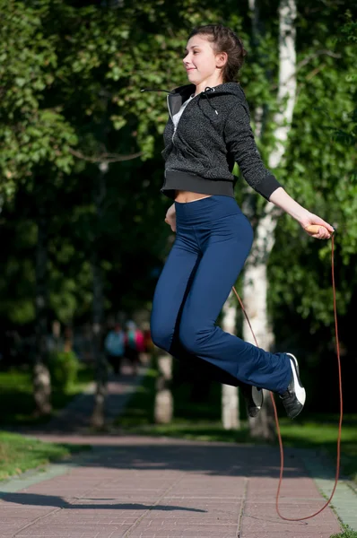 Hoppande kvinna med hopprep på park — Stockfoto