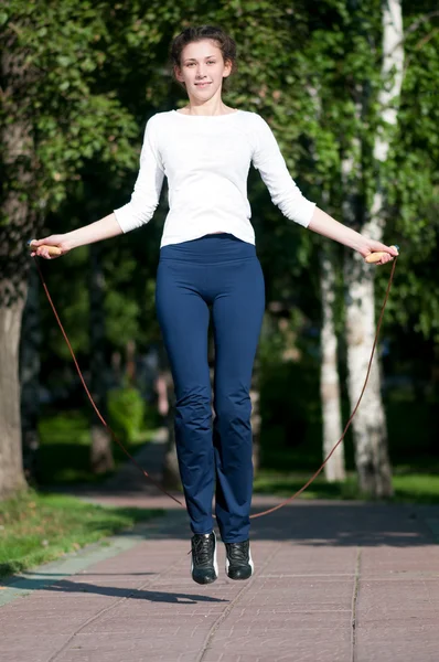 Прыгающая женщина с скакалкой в парке — стоковое фото