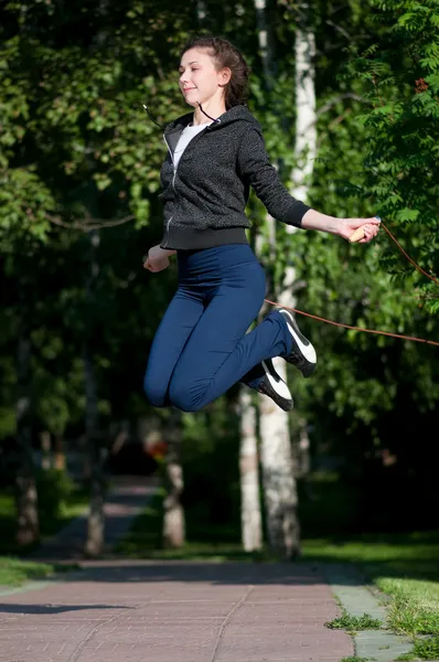 Стрибки жінки з пропускаючою мотузкою в парку — стокове фото