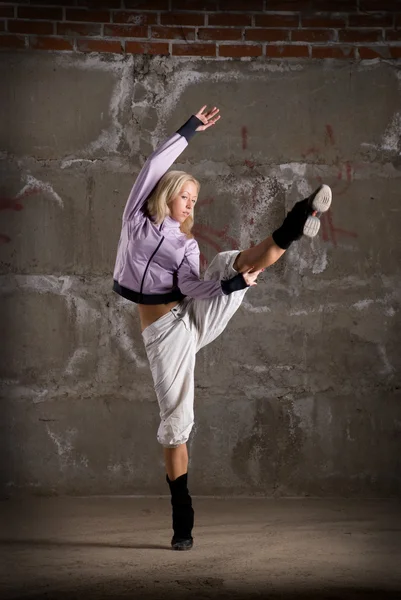 Красивая хип-хоп девушка танцует над серой кирпичной стеной — стоковое фото