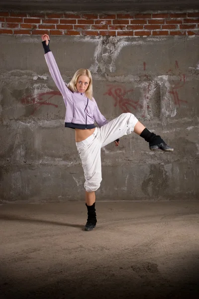Beautiful hip hop girl dancing over grey brick wall — Stock Photo, Image