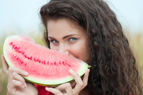 Frau im Weizenfeld, die Wassermelone isst. Picknick. — Stockfoto