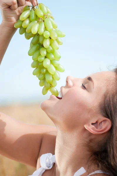 Perfect woman eating grapes in wheat field. Picnic. — Stock Photo, Image