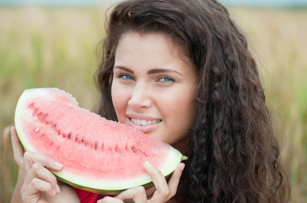 Frau im Weizenfeld, die Wassermelone isst. Picknick. — Stockfoto