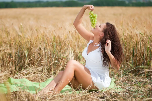 Perfecte vrouw druiven eten in tarweveld. picknick. — Stockfoto