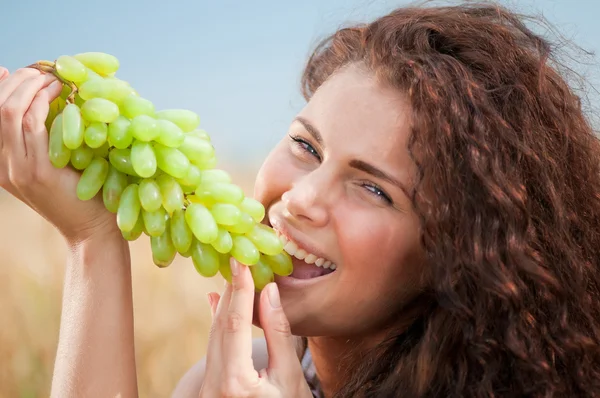 Donna perfetta che mangia uva nel campo di grano. Picnic . — Foto Stock