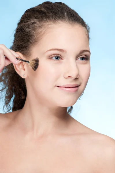 Młoda piękna dziewczyna robi makijaż przez szczotki — Zdjęcie stockowe