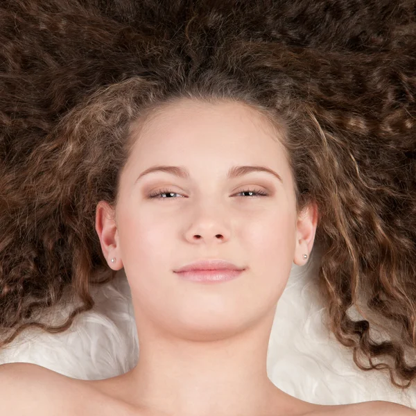 Tjej med perfekt lockigt hår liggande på päls säng — Stockfoto