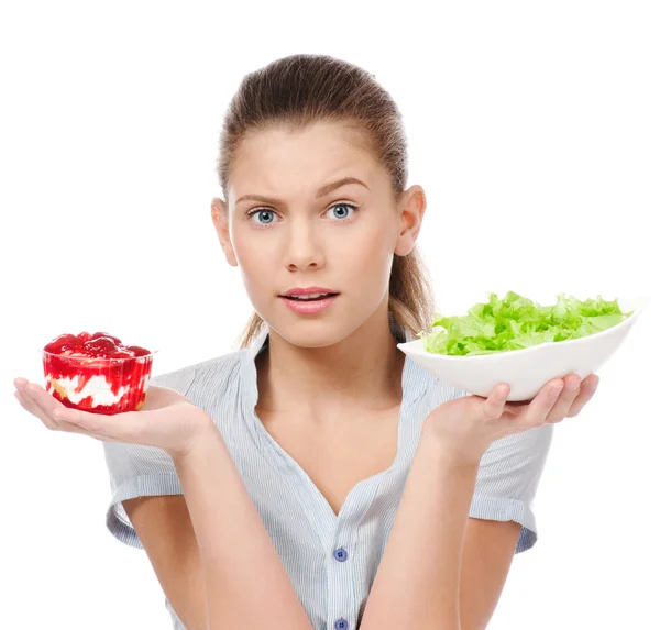 Pretty young woman choice salad or cake. Isolated — Stock Photo, Image