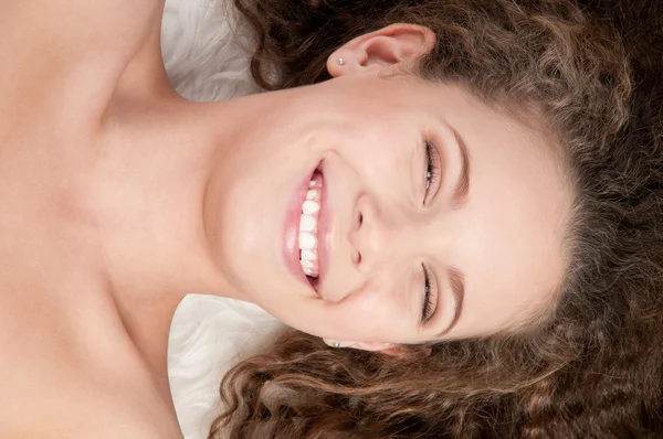 Mädchen mit perfektem lockigem Haar liegt auf Fellbett — Stockfoto