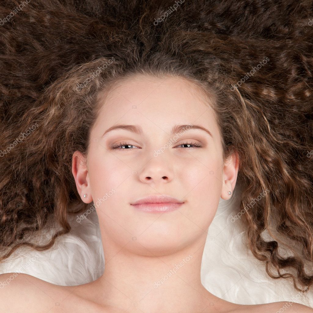 Girl with perfect curly hair lying on fur bed — Stock Photo © markin