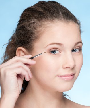 Young beautiful girl doing make-up by brush