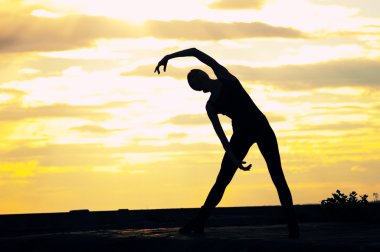 günbatımı üzerinde dansçı kadın silüeti. Yoga