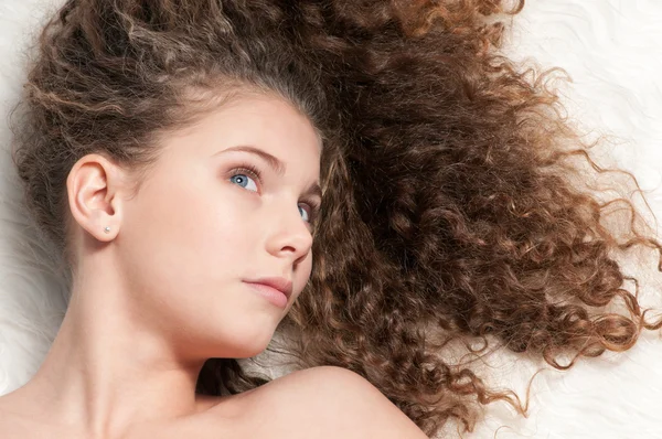 Chica con el pelo rizado perfecto acostado en la cama de piel — Foto de Stock