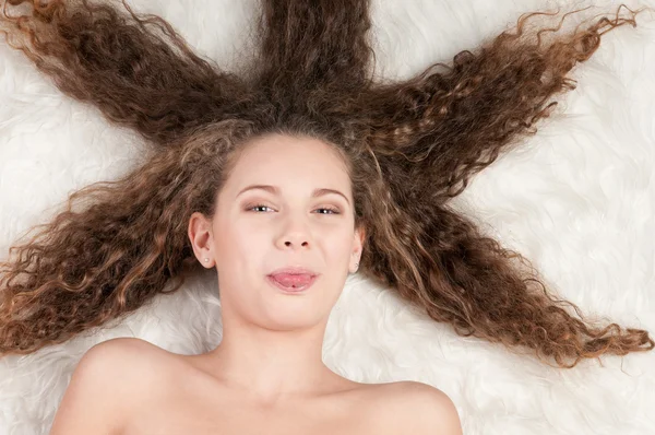 Κορίτσι με τέλεια σγουρά μαλλιά ξαπλωμένος στο κρεβάτι της γούνας — Φωτογραφία Αρχείου