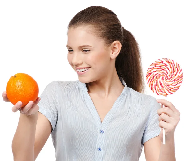 Ganska ung kvinna med lollipop och orange. Val — Stockfoto