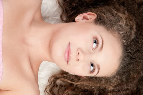 Девушка с идеальными вьющимися волосами лежит на меховой кровати — стоковое фото