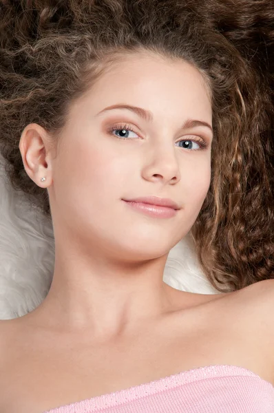 Дівчина з ідеальним кучерявим волоссям лежить на хутряному ліжку — стокове фото