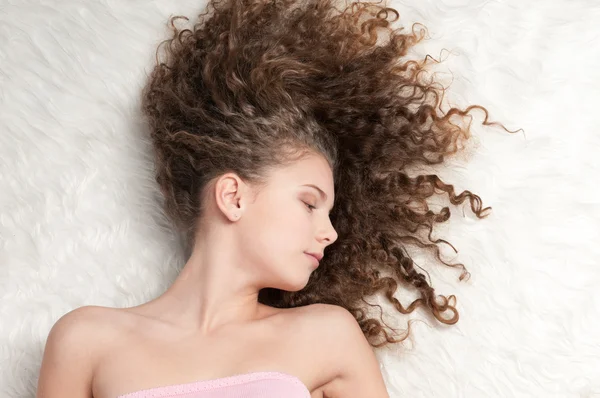 Chica con el pelo rizado perfecto acostado en la cama de piel —  Fotos de Stock