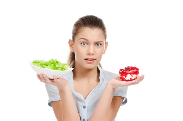 Pretty young woman choice salad or cake. Isolated — Stock Photo, Image